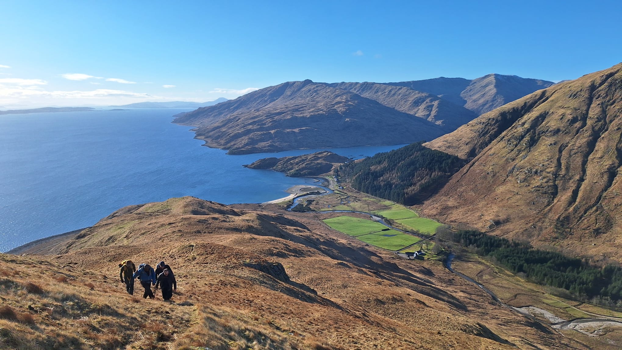people walking up a hill with blue sky and blue sea